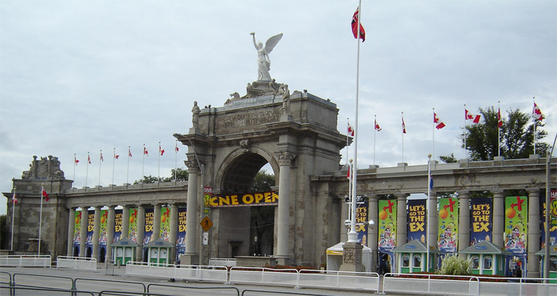 This is a photograph taken by Jesse Munroe (ExPlaceLover). It shows the Princes' Gate, the traditional entry to Exhibition Place in Toronto, Ontario.